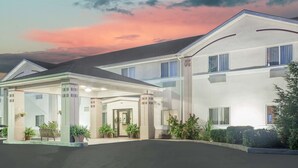 A hotel with a covered entrance, a reception desk, and a well-maintained garden.
