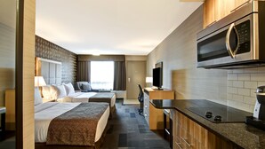 Habitación de hotel con dos camas, kitchenette, microondas y televisión.