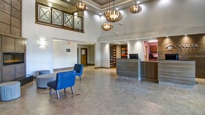 Un vestíbulo de hotel con una recepción, zona de estar y una chimenea.