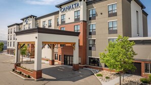 A multi-story hotel with a prominent "CANALTA" sign, a covered entrance, and a landscaped area with trees. - Canalta Hotel Cochrane (Cochrane)