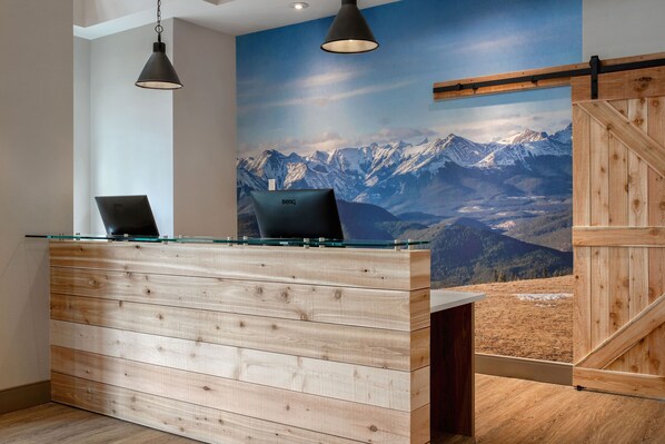 Reception area with a modern design, featuring a reception desk with laptops and a scenic mountain view.