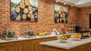 A modern kitchen with brick walls, stainless steel appliances, and a variety of fruits and vegetables on the counter. - Canalta Hotel Cochrane (Cochrane)