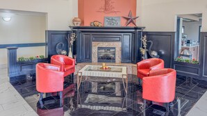 A lobby with a fireplace, red leather chairs, a star decoration, and a large mirror.