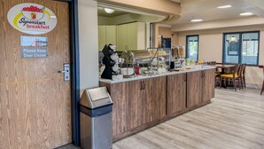 A breakfast area with a counter, food display, and seating.