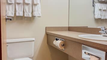 Un baño con inodoro, lavamanos y un toallero con toallas.