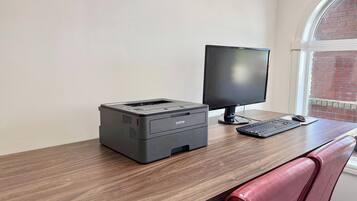 A workspace with a printer, monitor, keyboard, and mouse on a wooden desk.