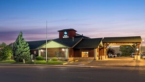 A Best Western hotel with a covered parking area and a large tree in front. - Best Western Yellowstone Crossing (Laurel)