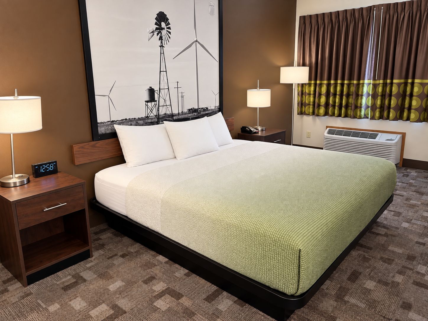 A hotel room with a large bed, two bedside tables, a wall clock, a window with curtains, and a wall-mounted air conditioner.