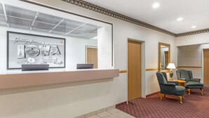 A reception area with a counter, chairs, and a mirror. - Super 8 by Wyndham Cresco IA (Cresco)