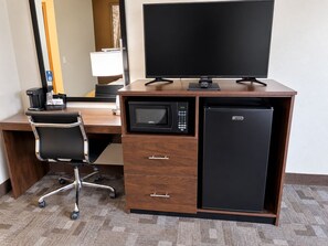 A hotel room with a wooden desk, a black office chair, a flat-screen TV, a microwave, a mini-fridge, and a coffee maker. - Super 8 by Wyndham Cresco IA (Cresco)