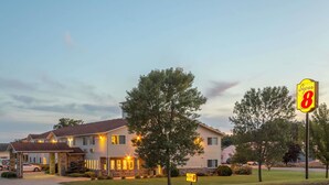 A motel with a Super 8 sign, a covered parking area, and a well-maintained lawn. - Super 8 by Wyndham Cresco IA (Cresco)