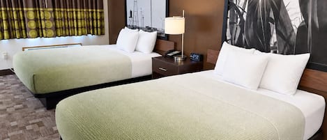 Habitación de hotel con dos camas, una mesita de noche, una lámpara y un cuadro de molinos.