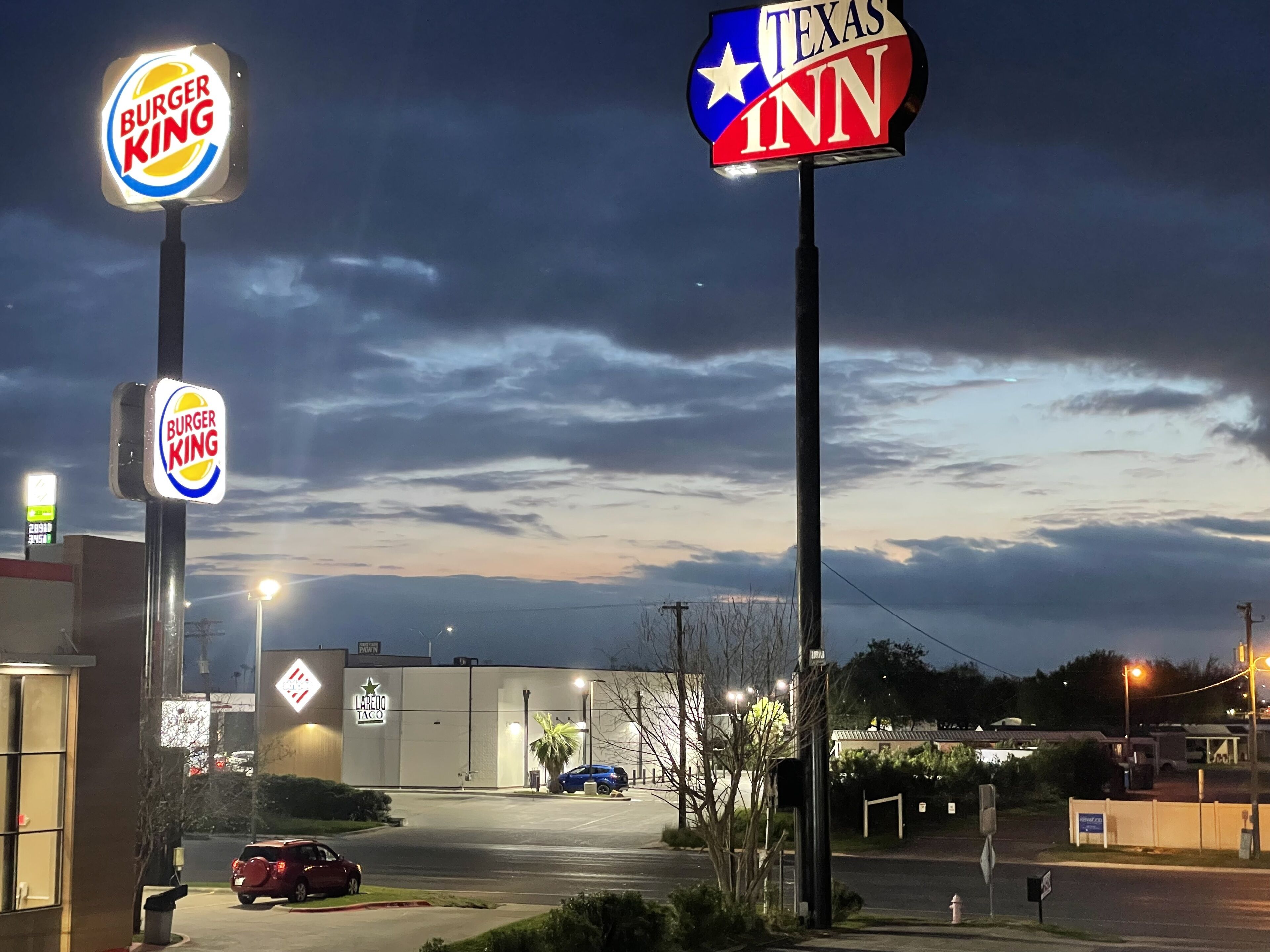 Un parking avec des panneaux indiquant la présence d’un restaurant Burger King et d’un autre appelé Texas Inn.