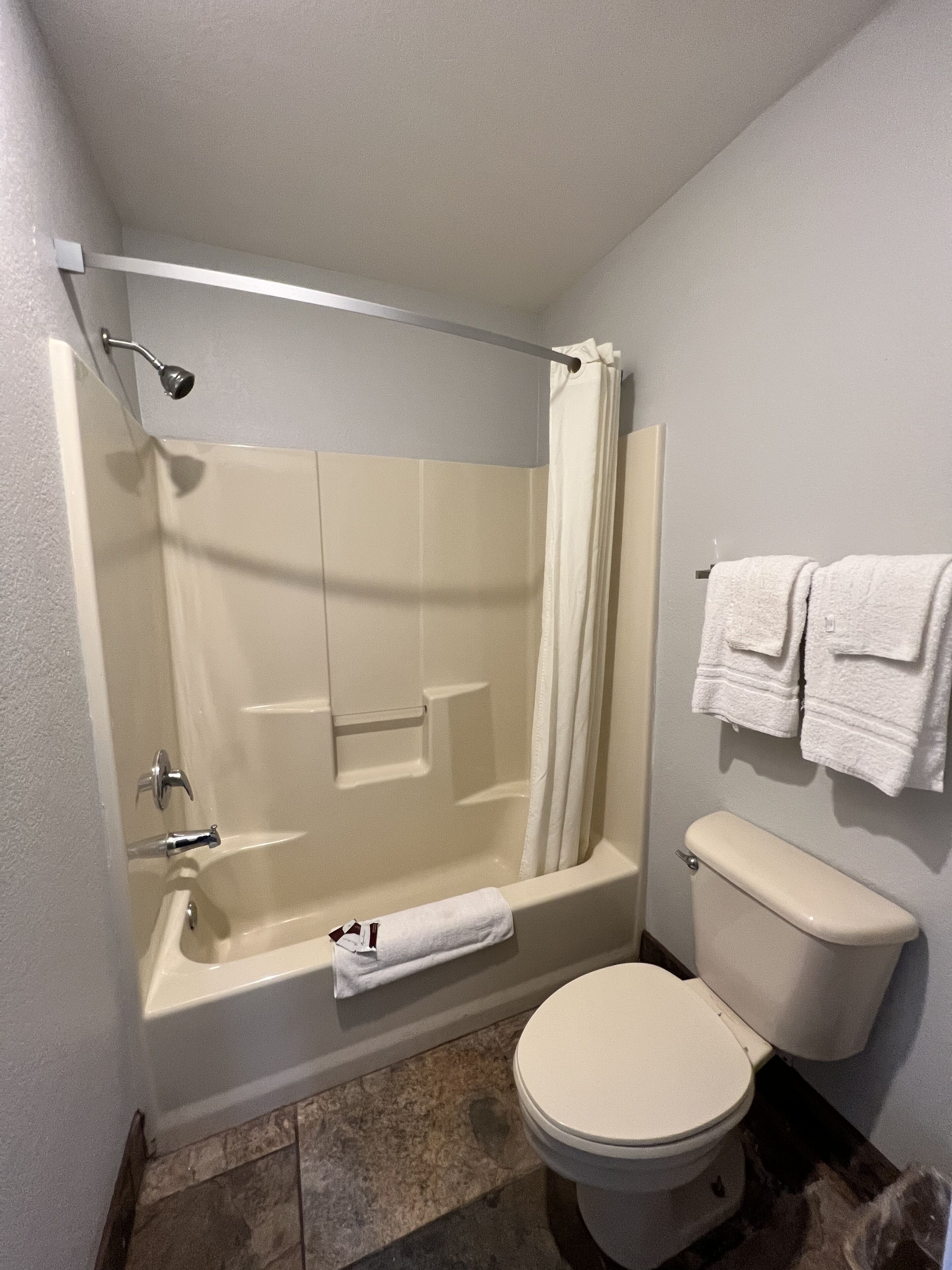 Un baño con bañera, ducha, inodoro y un perchero para toallas.