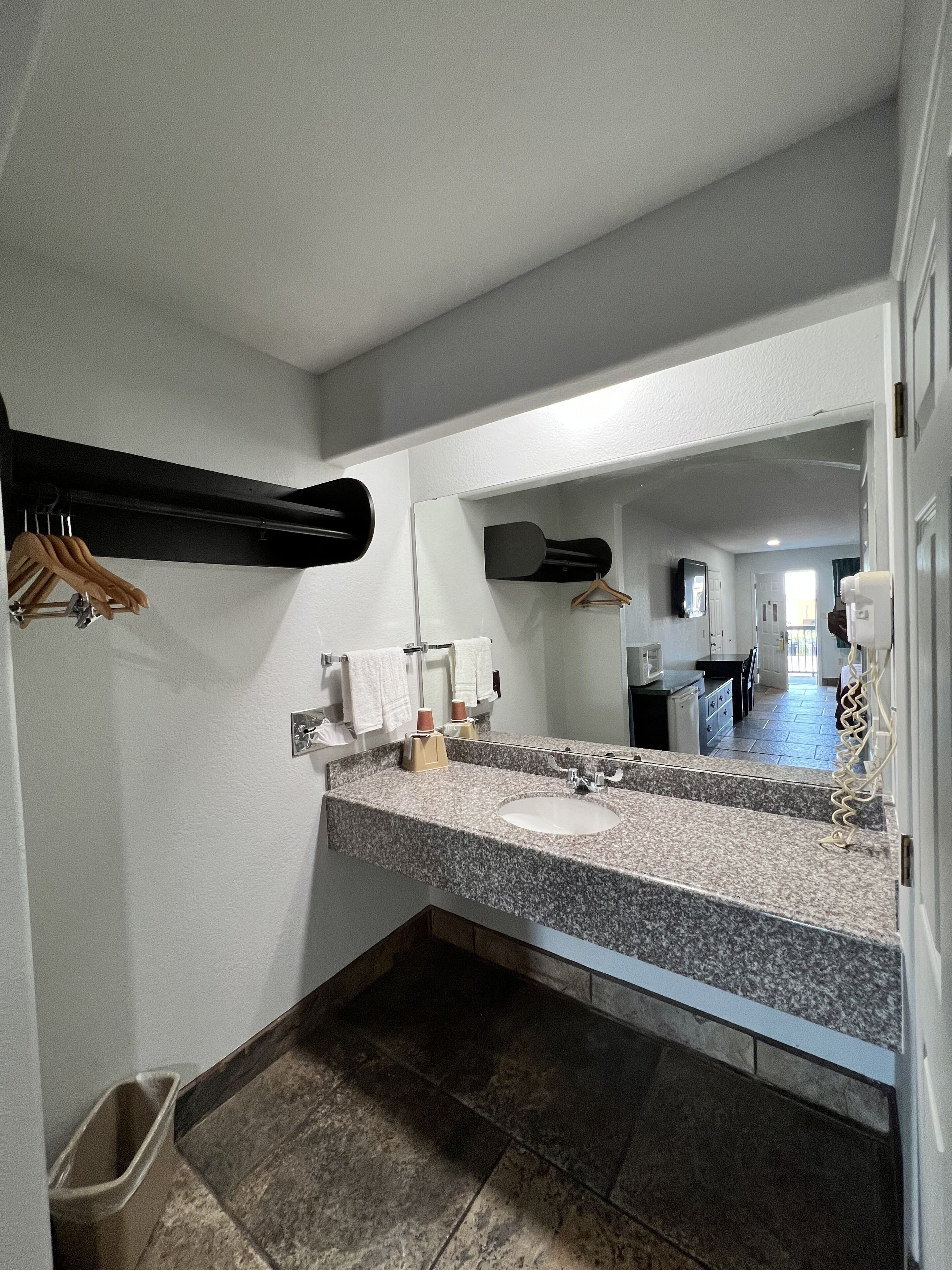 A bathroom with a granite countertop, a sink, a mirror, and a towel rack.