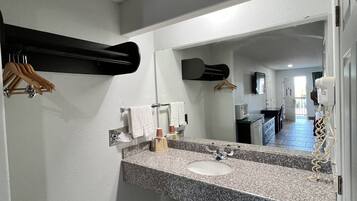 A bathroom with a granite countertop, a sink, a mirror, and a towel rack.