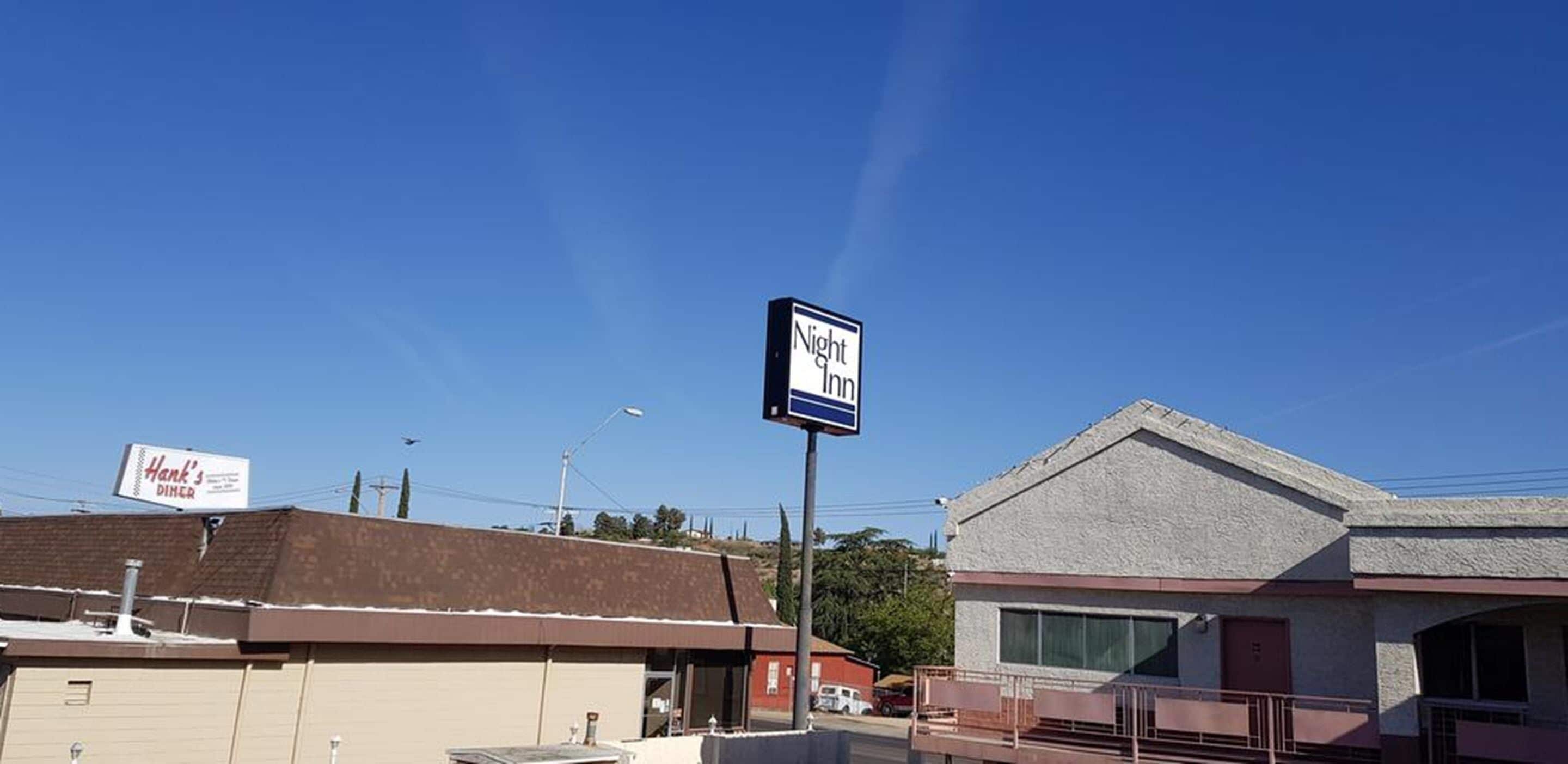 A building with a sign for "Night Inn" and another sign for "Hank's Diner" in a clear sky.