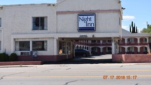 Un bâtiment avec une enseigne indiquant « Night Inn », un parking et une voiture garée devant.