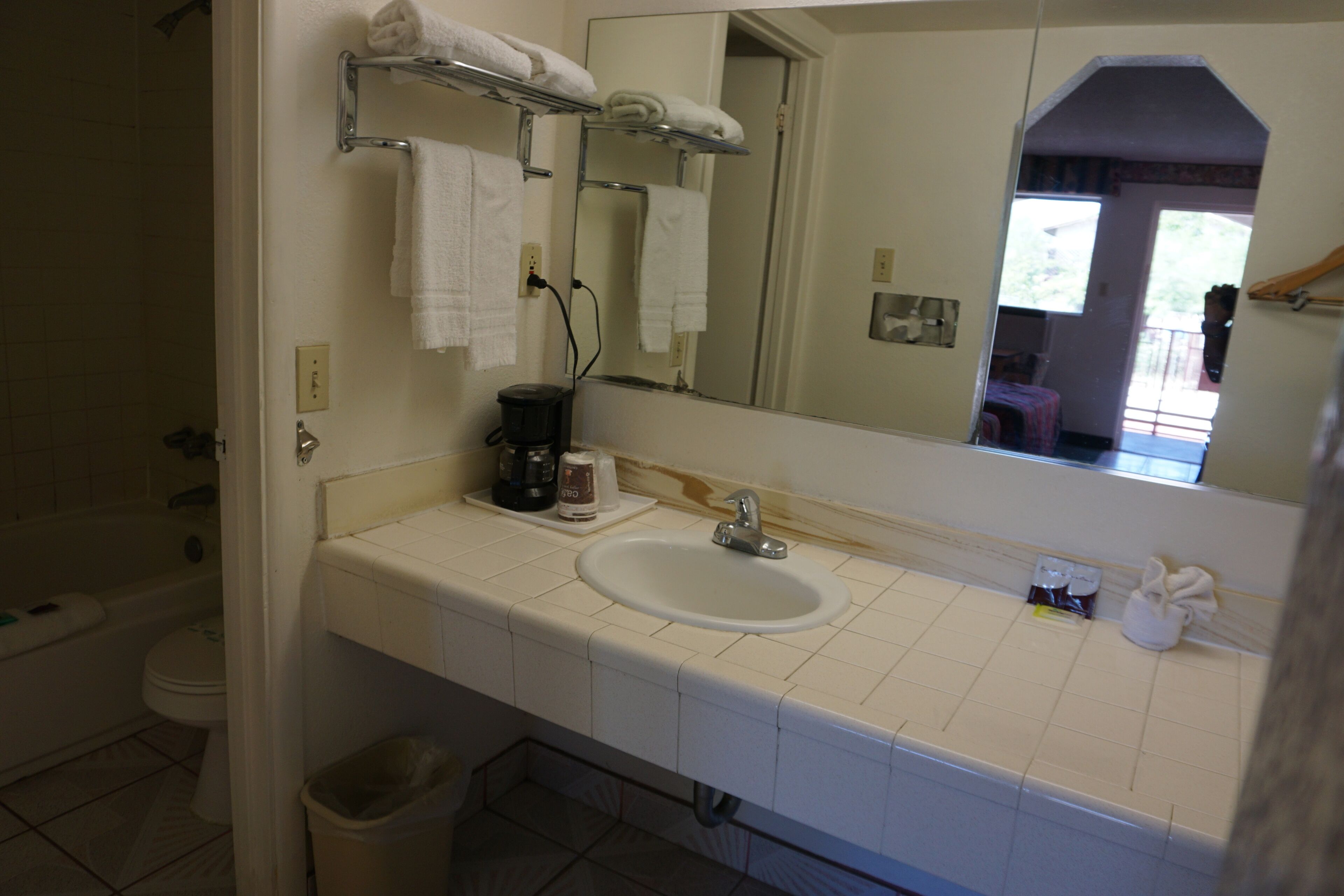 A bathroom with a white sink, a mirror, and a towel rack.