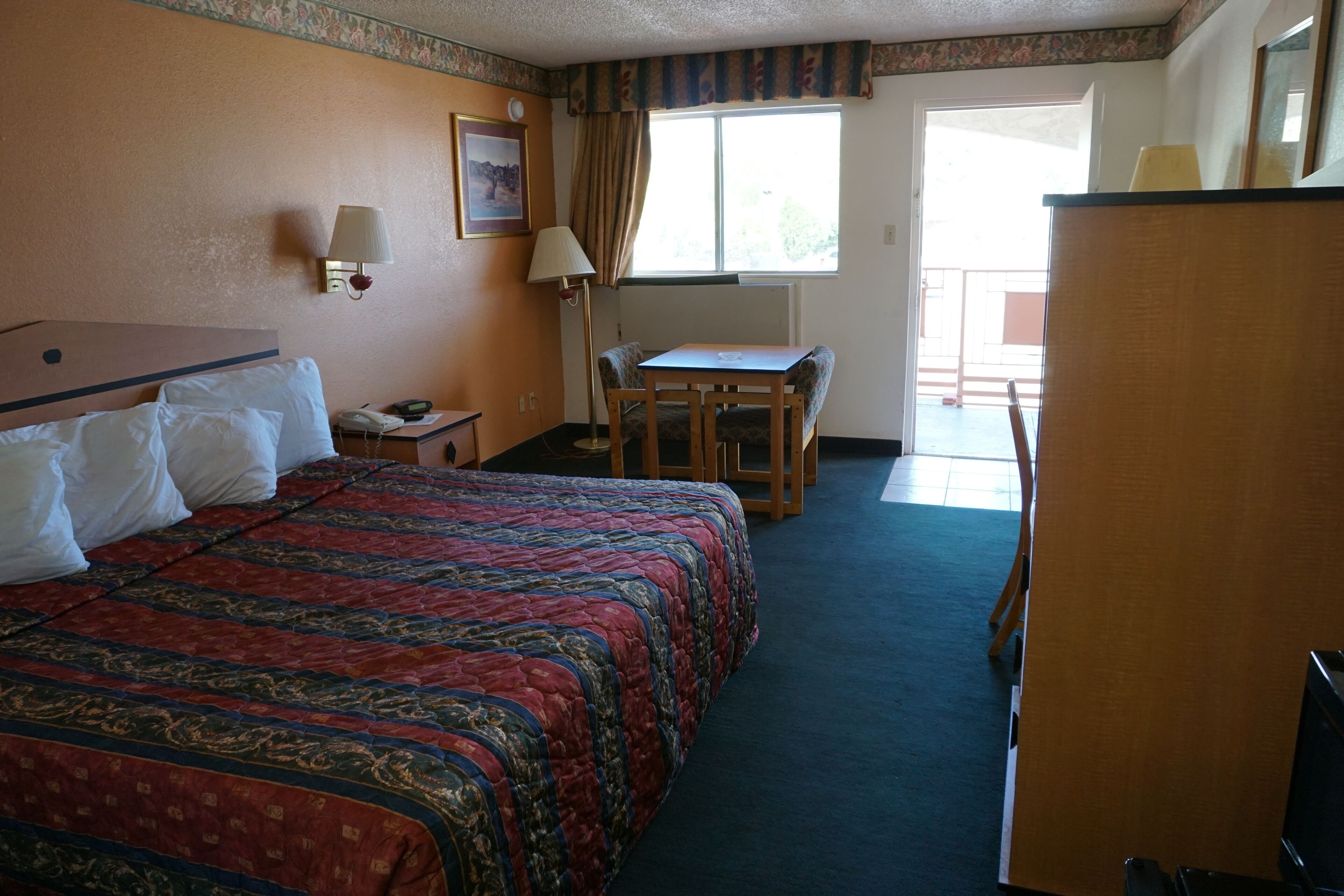 Una habitación de hotel con una cama grande, un escritorio, una silla, una lámpara y una ventana.