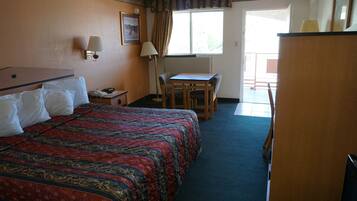 Una habitación de hotel con una cama grande, un escritorio, una silla, una lámpara y una ventana.
