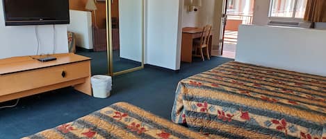A hotel room with two beds, a TV, a desk, and a chair.