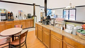 Una cocina con armarios de madera, encimera de granito, máquina de café, tostadora y refrigerador.