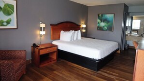 A hotel room with a large bed, wooden nightstand, and a small desk.