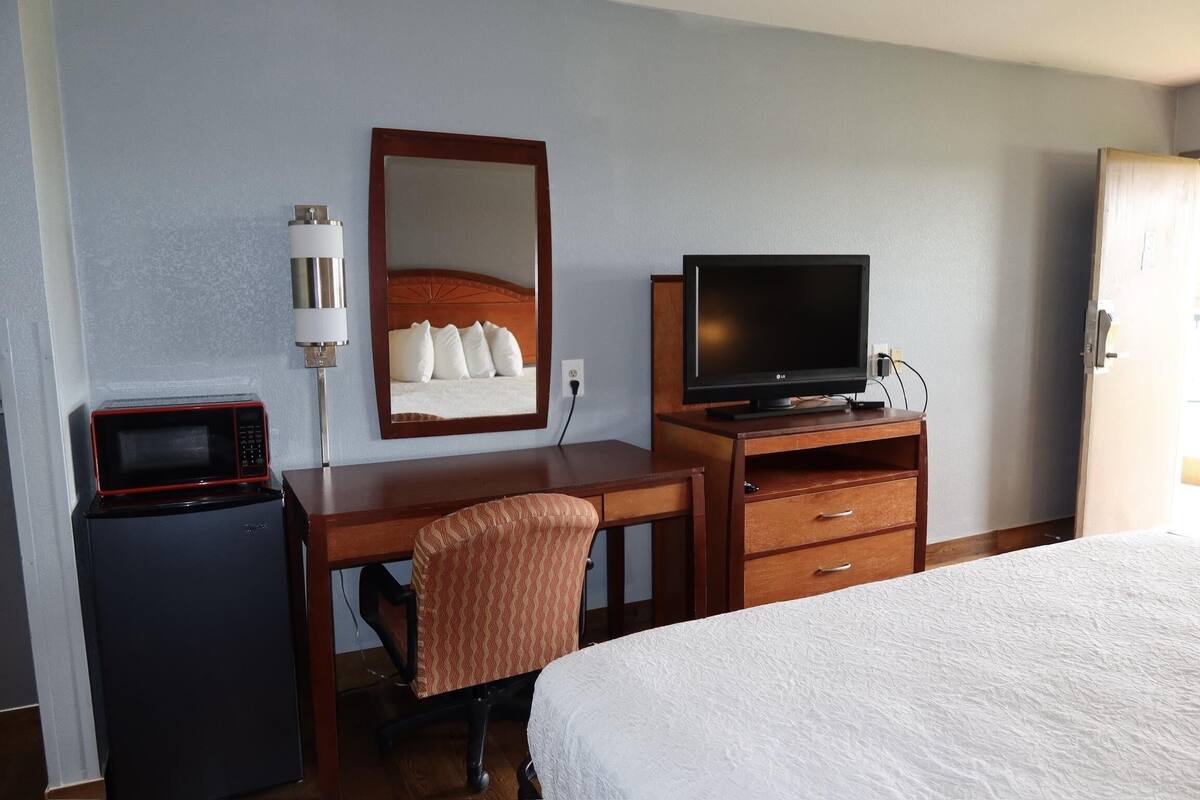 Une chambre d’hôtel comprenant un lit, un bureau avec une télévision, un four à micro-ondes et une chaise.