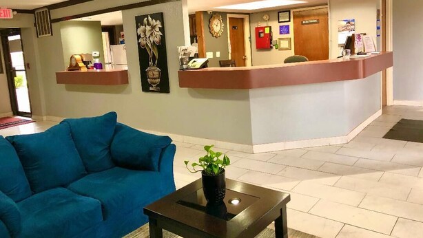 A reception area with a counter, a clock, and a plant on a table.