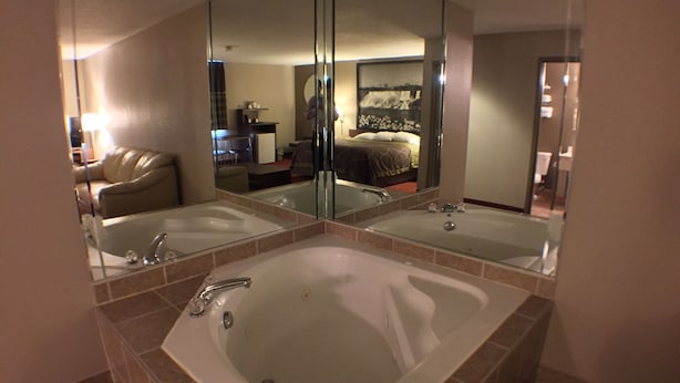 Une salle de bain dotée d’une grande baignoire, d’un lavabo double et d’un miroir qui reflète la pièce.