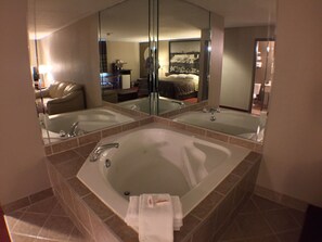 Une salle de bain dotée d’une grande baignoire, d’un lavabo double et d’un miroir qui reflète la pièce.