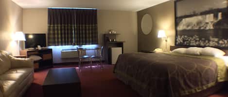 A hotel room with a bed, a desk, a chair, a sofa, a television, and a painting on the wall.