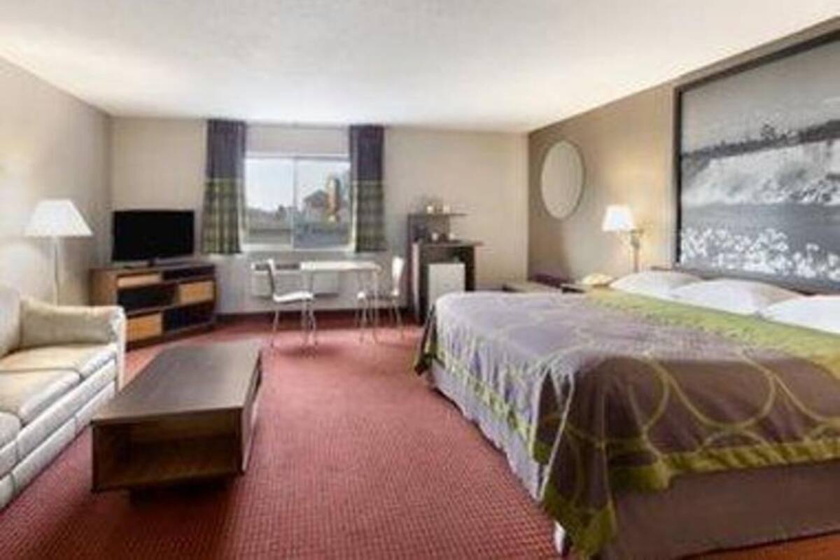 Ein Hotelzimmer mit Bett, Schreibtisch, Stuhl, Fernseher und Fenster.