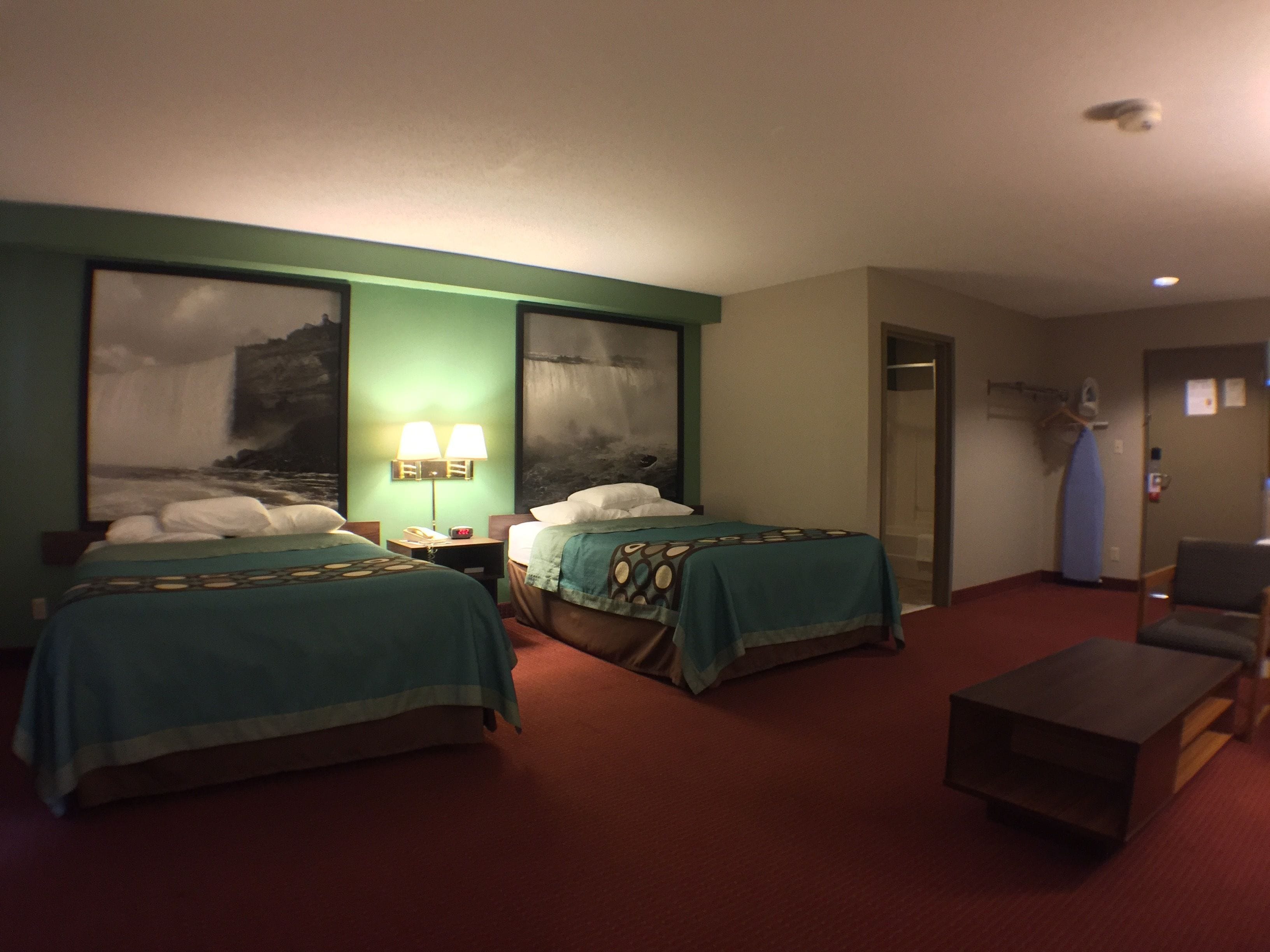 Habitación de hotel con dos camas, un escritorio, una silla y zona de ducha.