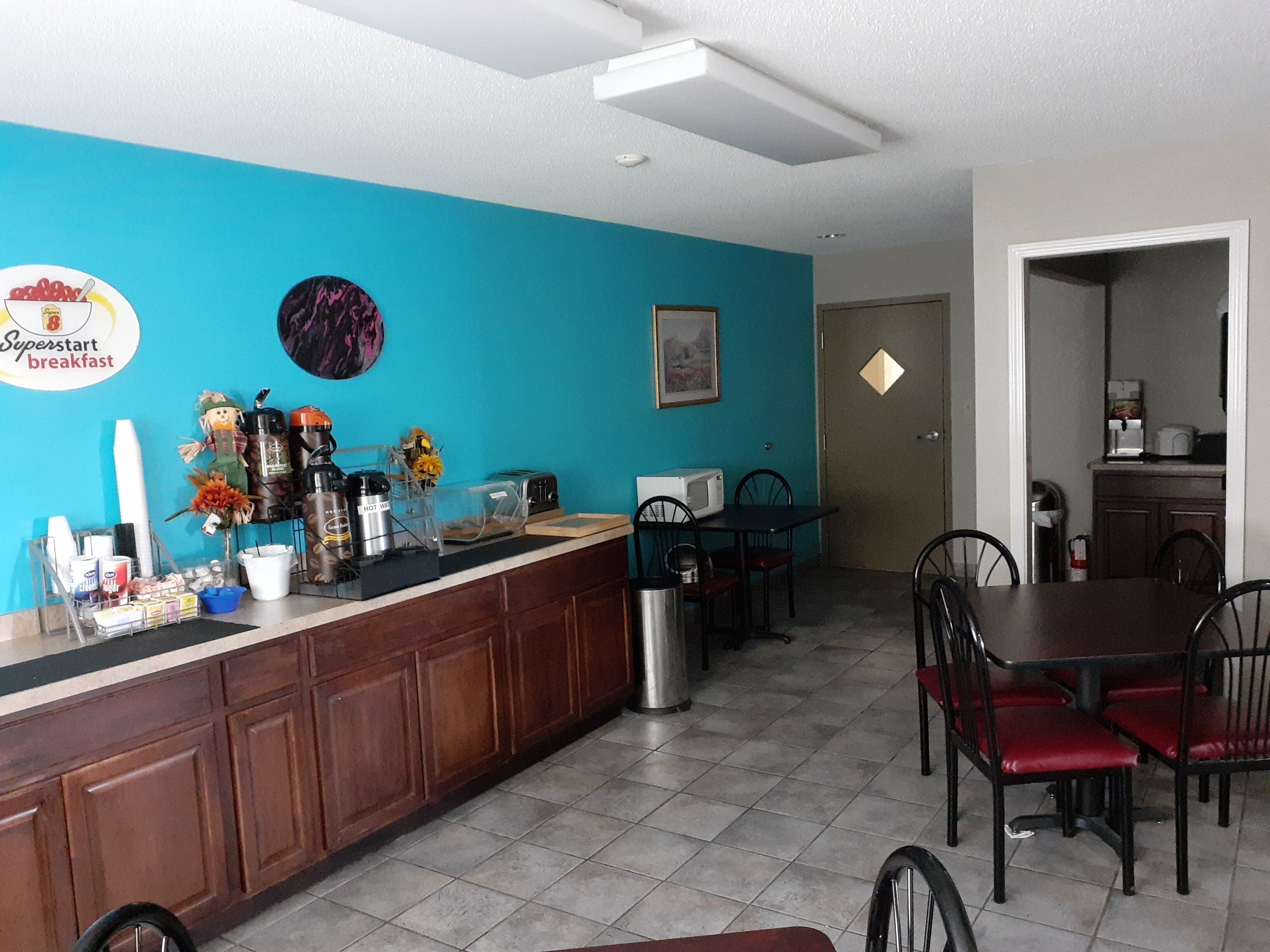 A breakfast bar with a sign, a microwave, and a toaster. There are chairs and a table in the dining area.