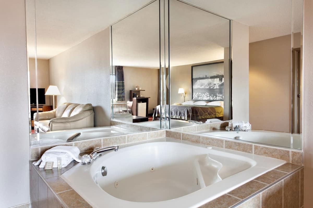 Ein Hotelbad mit einer großen Badewanne, einem Spiegel und einer Sitzecke mit Sofa und Sessel.