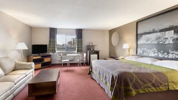 Ein Hotelzimmer mit Bett, Sofa, Schreibtisch, Fernseher und einem großen Fenster mit Vorhängen.
