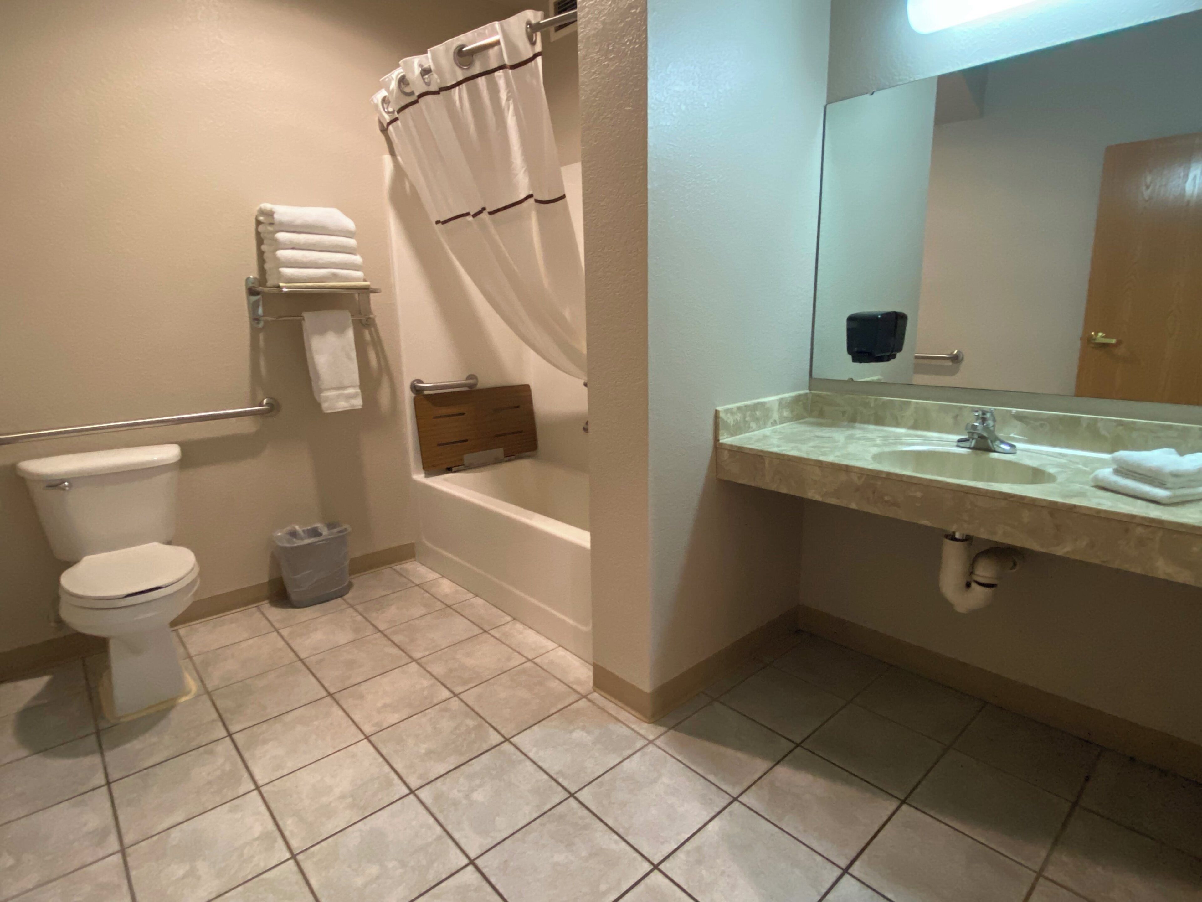 Un baño con inodoro, bañera, tocador con lavamanos y espejo.