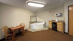 Une pièce comprenant une table à manger, des chaises, un coin cuisine avec un four à micro-ondes et une baignoire.