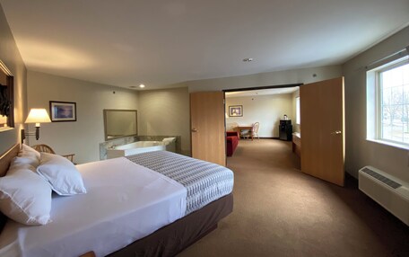 A hotel room with a bed, a desk, a chair, a bathroom with a bathtub, and a window.