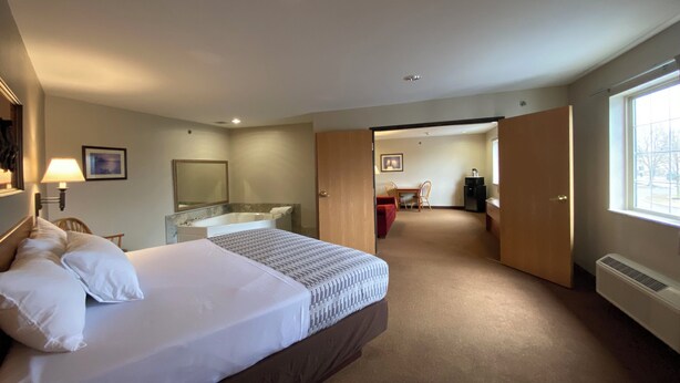 Une chambre d’hôtel comprenant un lit, un bureau, une chaise, une salle de bain avec baignoire et une fenêtre.