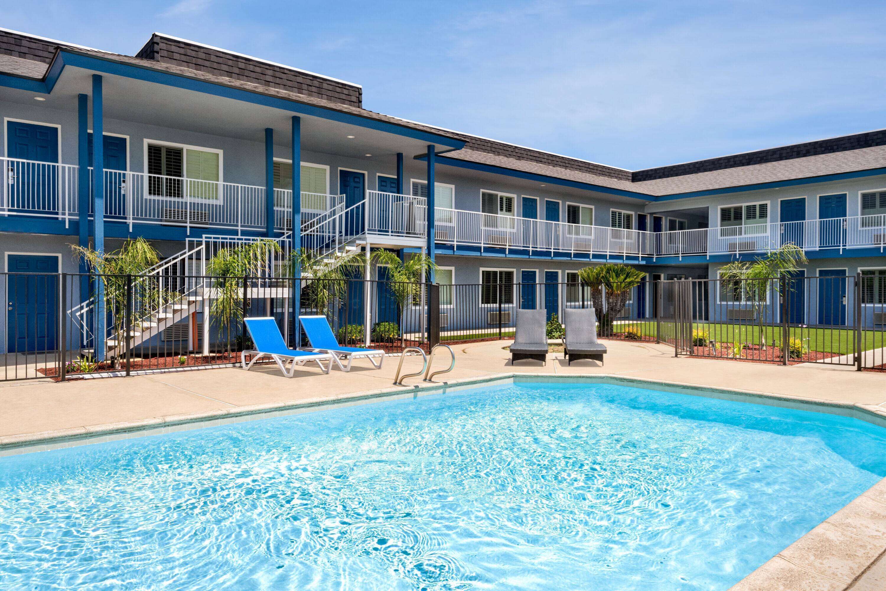 A hotel with a pool area, including lounge chairs and a staircase leading to the upper floors.