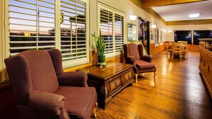A spacious room with large windows, a wooden floor, and a seating area with two armchairs and a small table. - Super 8 by Wyndham Lindsay Olive Tree (Lindsay)