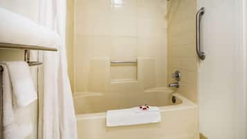 Une salle de bain équipée d’une baignoire, d’une barre d’appui et d’un porte-serviettes avec des serviettes.