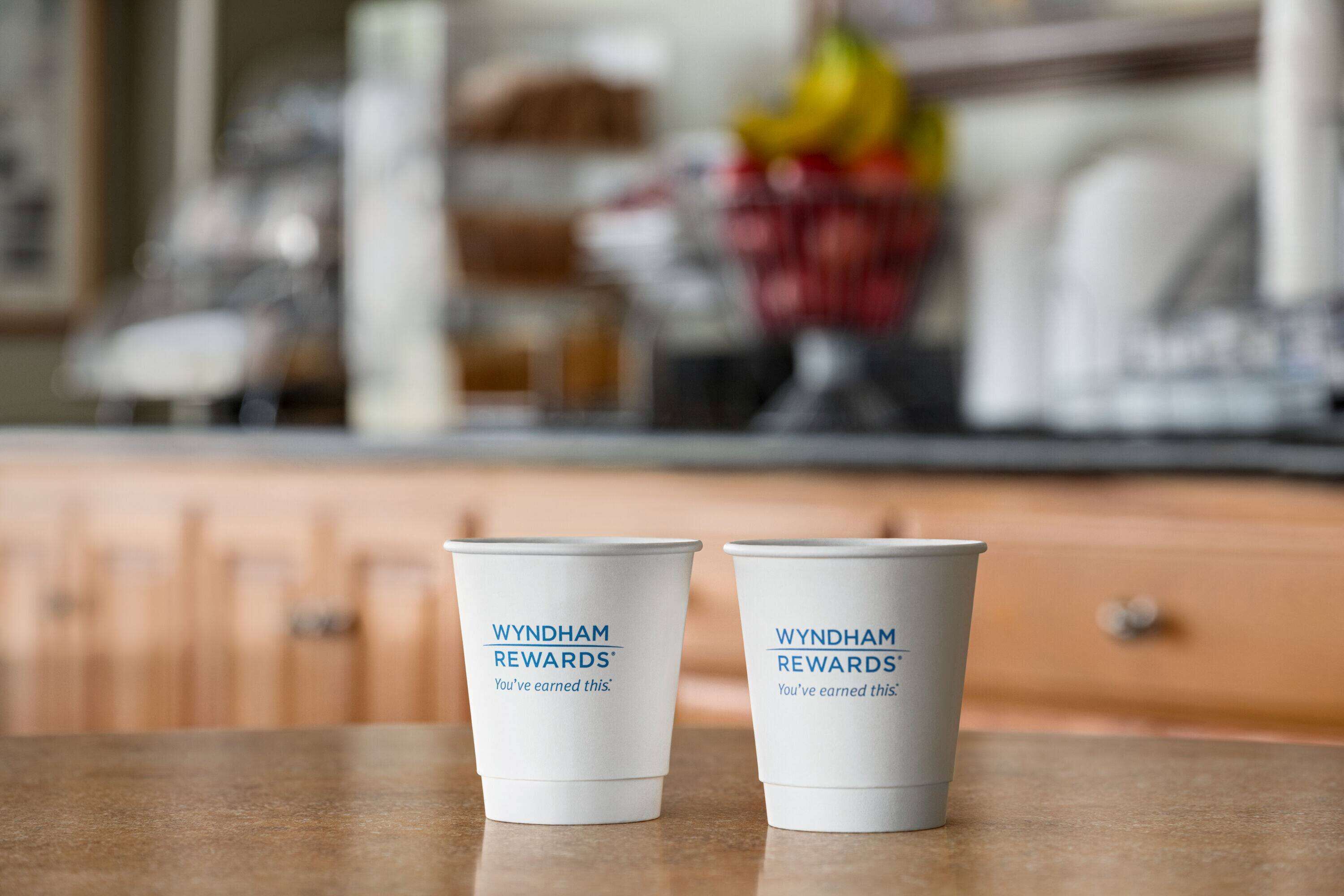 Deux tasses blanches ornées du logo « Wyndham Rewards » sont posées sur un comptoir.