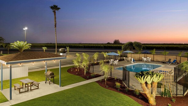 A covered outdoor area with a barbecue, seating, and a pool. - Super 8 by Wyndham Lindsay Olive Tree (Lindsay)