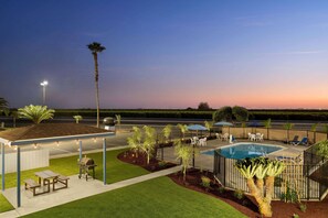 A covered outdoor area with a barbecue, seating, and a pool. - Super 8 by Wyndham Lindsay Olive Tree (Lindsay)