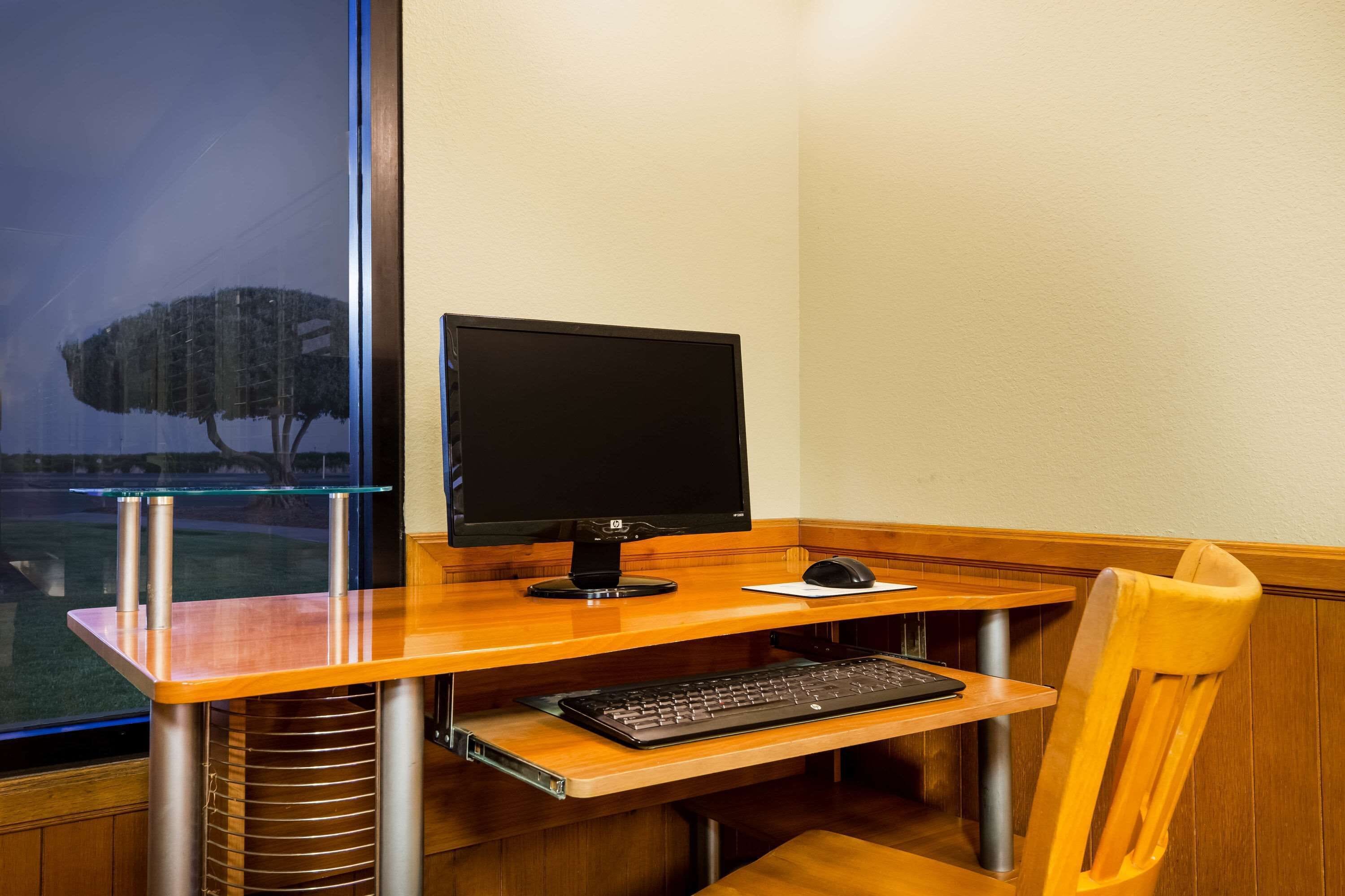 A wooden desk with a computer monitor, keyboard, and mouse.