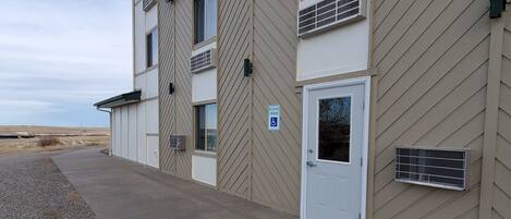 Un bâtiment à la façade beige, avec une porte blanche et un panneau indiquant que le stationnement est réservé.